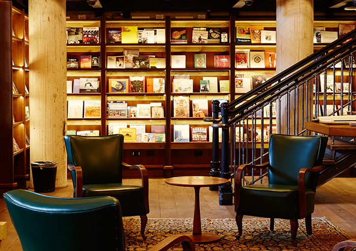 A cinematic close-up shot of the spine of a first-edition book on Frank Lloyd Wright in Hotel Emma's library, with the worn cover and faded gold lettering, capturing the essence of architectural history.