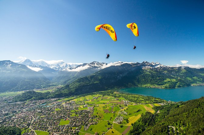 A paraglider soaring over Interlaken, with the turquoise lakes and snow-capped mountains providing a stunning backdrop.