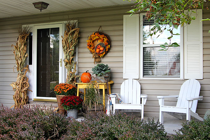 a close-up of pumpkins and gourds arranged on a porch