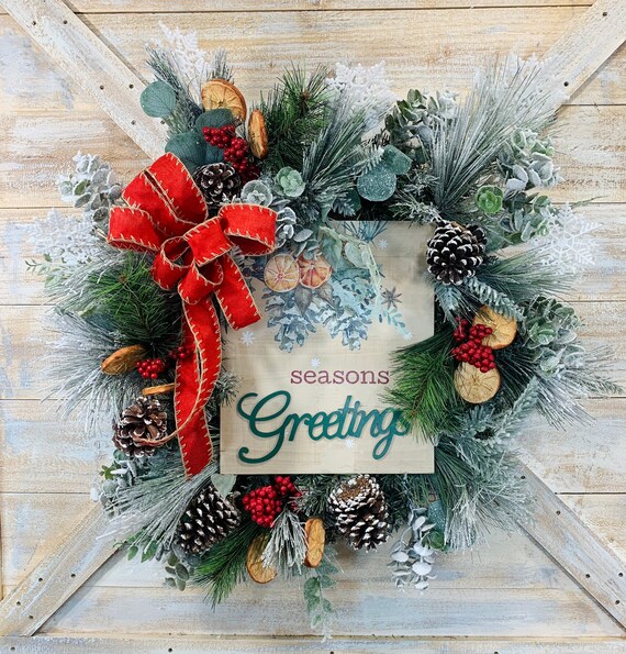 A natural holiday wreath hanging on a weathered wooden door, showcasing its rustic charm and welcoming presence.