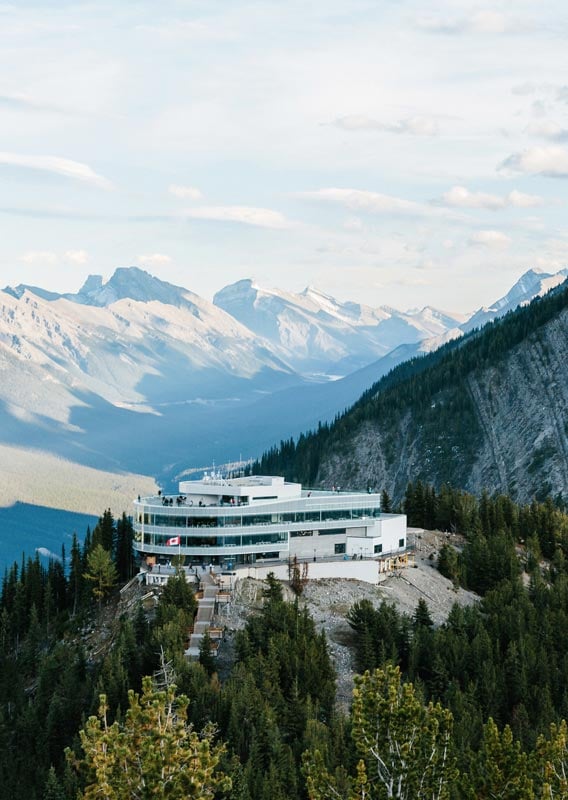 A wide-angle landscape photo capturing the full expanse of the valley with the Bow River snaking through it, taken from Sulphur Mountain.