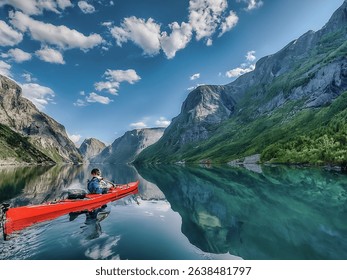 A kayaker paddles through the calm, glassy waters of a Norwegian fjord. Towering granite cliffs rise dramatically on either side, and a waterfall is visible in the distance.