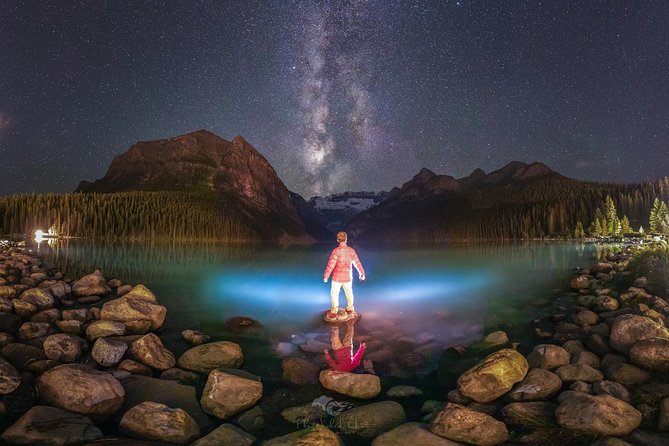 Moraine Lake's turquoise waters surrounded by golden larches in autumn, viewed from the Rockpile Trail with several other hikers visible.