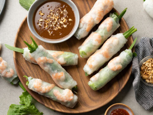 A plate of Goi Cuon, showcasing the translucent rice paper, vermicelli noodles, herbs, and dipping sauce.
