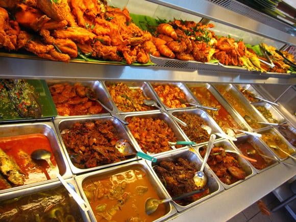 A spread of Nasi Kandar dishes, showcasing the variety of curries, fried chicken, and side dishes available at Hameediyah Restaurant.