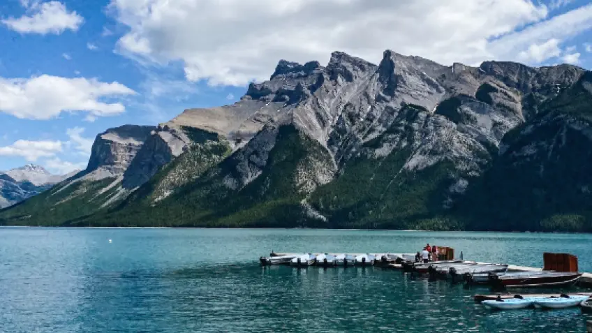 A frozen Lake Minnewanka covered in methane ice bubbles, with snow-capped mountains in the background, illustrating the beauty of Banff's winter landscapes and the potential for stunning ice bubble photography.