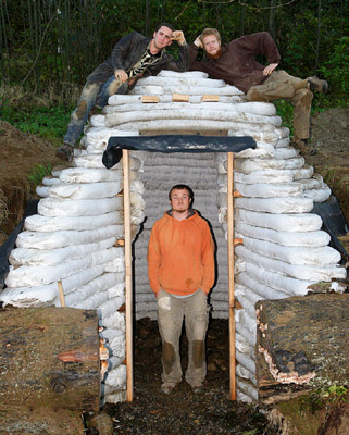 A completed earthbag root cellar is nestled into the landscape, showcasing the finished dome structure.