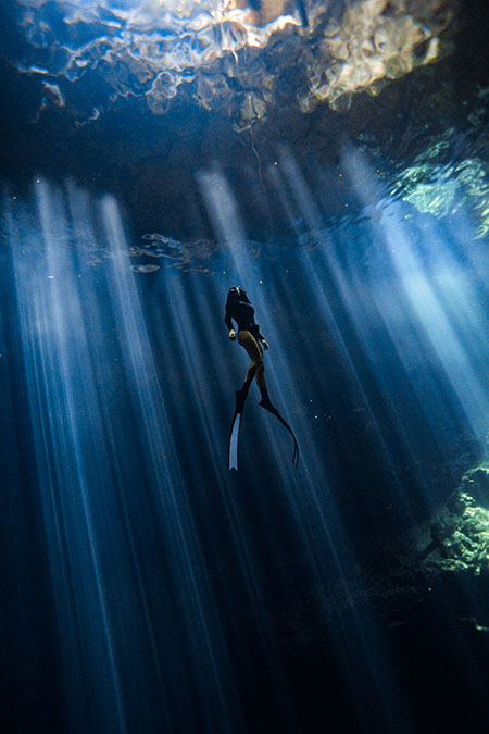 A kayak glides through Mosquito Bay, leaving trails of shimmering bioluminescence in the water, showing the beauty of this natural wonder.