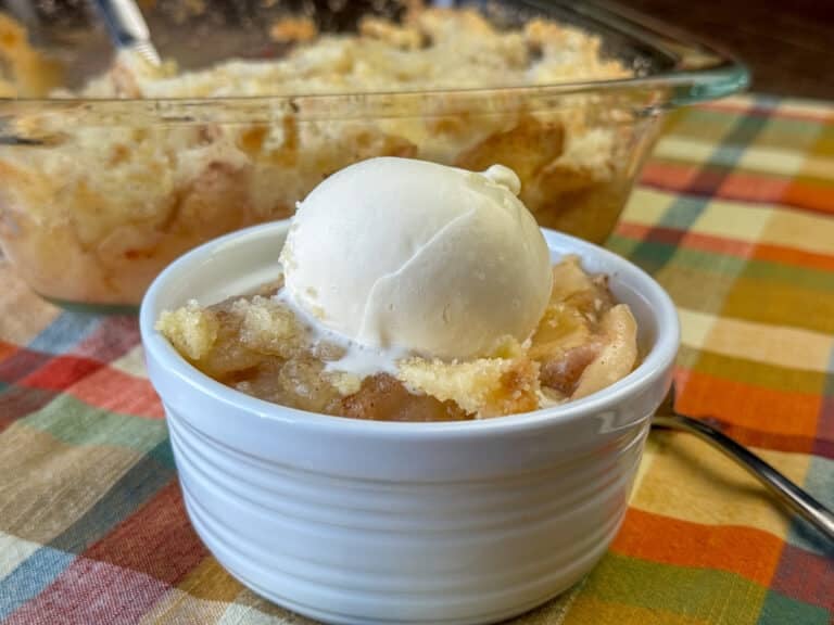 Arrangement of ingredients for apple crisp, including apples, oats, butter, cinnamon, and brown sugar.