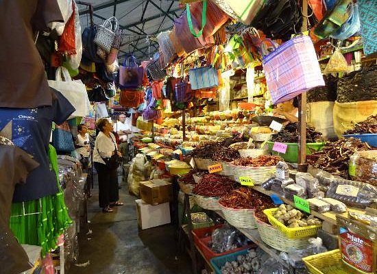 A table setting at a restaurant in Oaxaca, featuring a dish of mole negro, side dishes, and drinks.