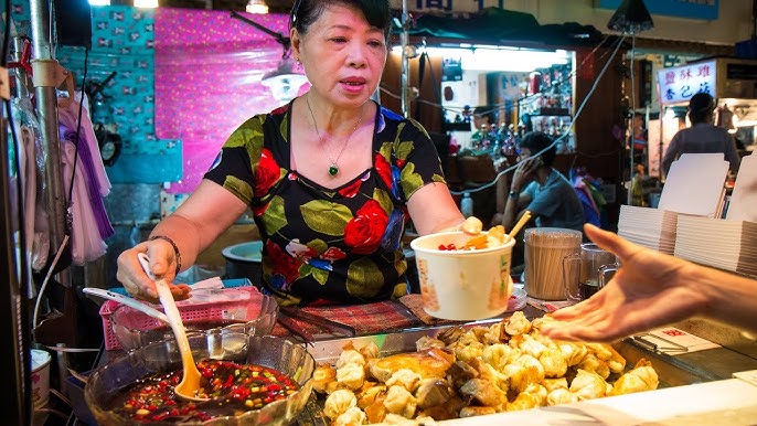 A wide shot of Raohe Night Market, capturing the crowds, the neon lights, and the variety of food stalls.