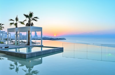 The rooftop pool at sunset, featuring reflections of city lights and the Bahrain World Trade Center.
