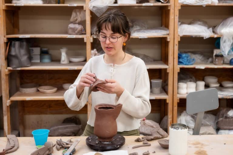 A pathway through a lush green forest with sunlight streaming through the canopy, illustrating a forest bathing experience. The alt text describes the serene environment and healing effect of forest bathing at the NC Arboretum