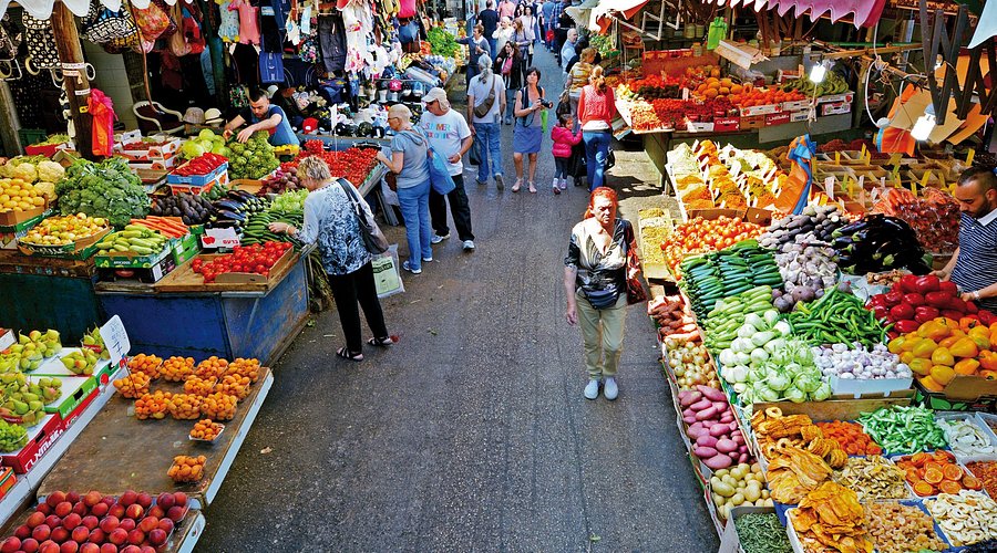 Shuk HaCarmel Market in Tel Aviv bustling with shoppers and vendors, displaying a variety of fresh produce, spices, and baked goods, representing the vibrant heart of Tel Aviv's food culture