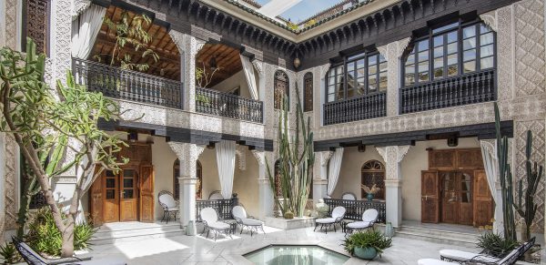 An inner courtyard of a traditional riad in Marrakech, showcasing the intricate tilework, lush greenery, and serene atmosphere. This image embodies the tranquility and beauty found within these hidden gems.