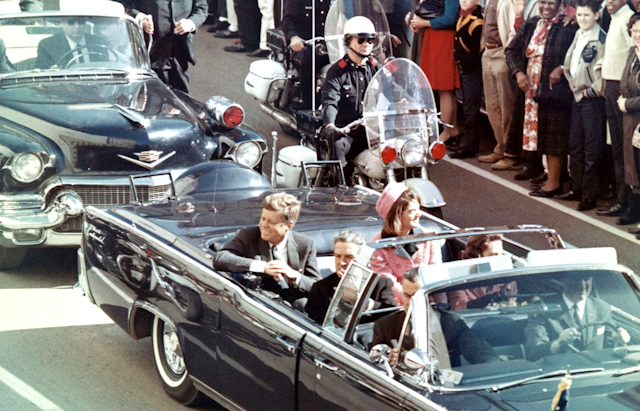 A close-up, marked-up forensic photograph of Zapruder film frame 313, with hand-drawn annotations in red ink highlighting key details such as the head wound and the direction of Kennedy's head movement.
