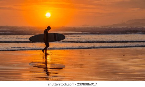 A surfer riding a wave at Cox Bay with mist in the background.