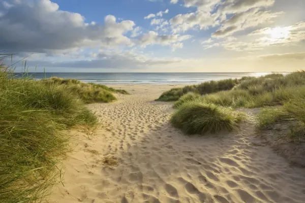 Bamburgh Castle overlooks the vast, windswept beach under a moody, overcast sky. Texture of sand and castle are visible