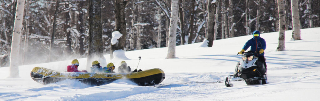 Wide shots of snowmobiles traversing the snow-covered landscape, close-ups of snow-covered trees, aerial views showcasing the volcanic terrain