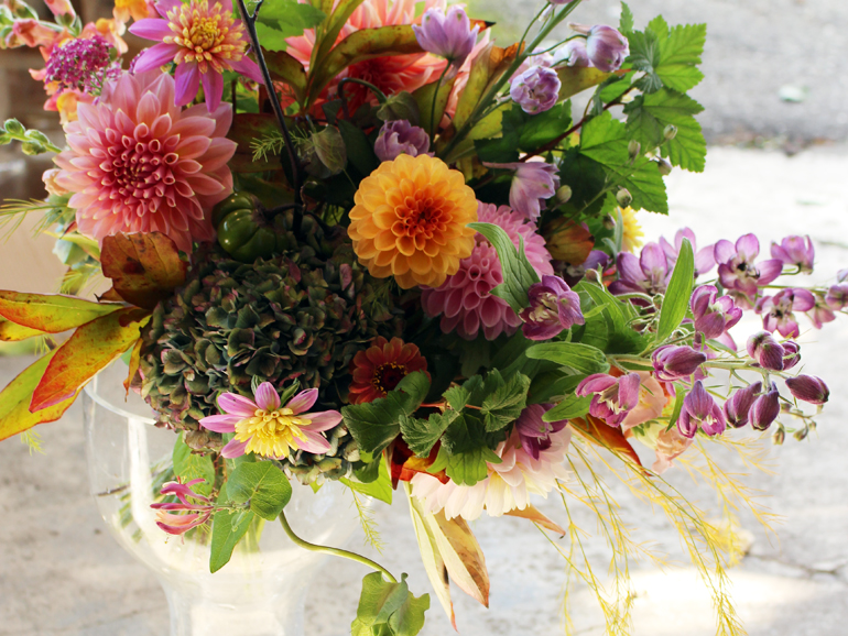 Close-up shot of hands arranging dried hydrangeas in a rustic wooden bowl