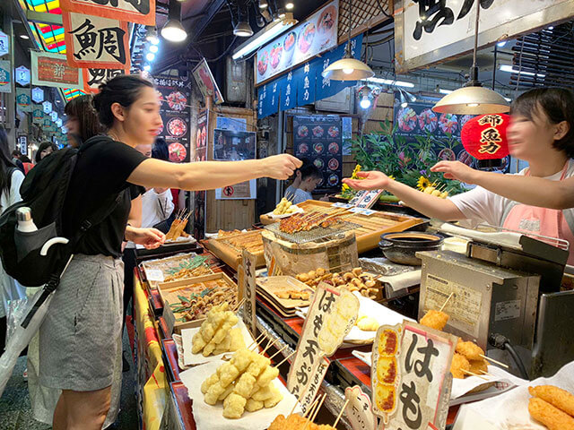 A vibrant and bustling scene from Nishiki Market, showcasing the diversity and energy of Kyoto's street food culture