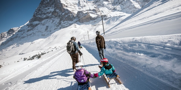The Bergwelt Grindelwald Alpine Design Resort nestled in the snow-covered mountains, showcasing its modern architecture and sustainable design. The alt text highlights the use of local timber and geothermal energy.