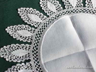 Close-up of delicate embroidery along the edge of a linen doily, showcasing intricate crochet detailing.