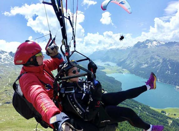 A breathtaking view of someone paragliding over snow-capped mountains, showcasing the vastness and beauty of the Swiss Alps.