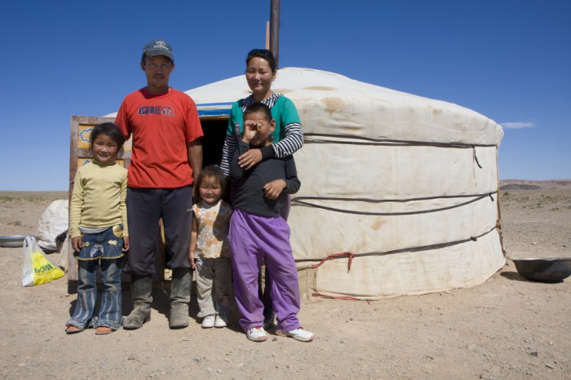 Dr. Sharma setting up her telescope outside the yurt at night, the Milky Way stretching across the dark sky behind her.