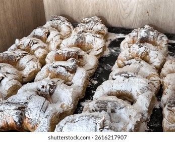 Close-up of a freshly baked medialuna glistening under warm bakery lighting.