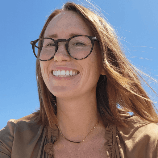 A woman smiling in a bookstore holding a book