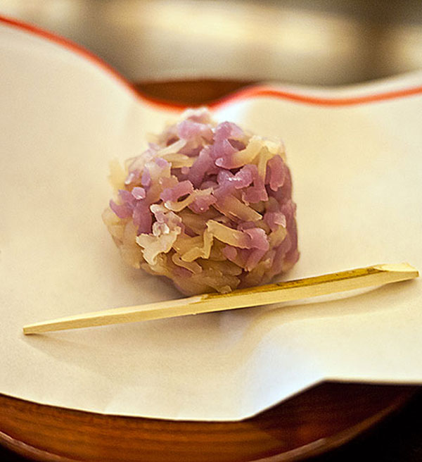 A bowl of kuzu-kiri, showcasing the translucent noodles in a dark syrup, with the shop's wooden interior in the background, evoking a sense of tradition.