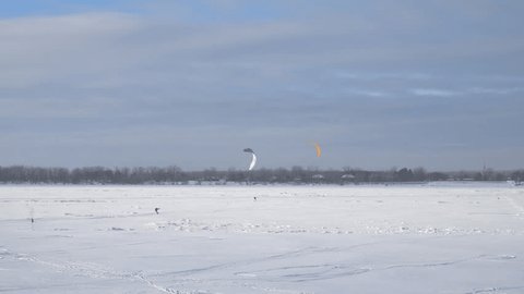 Snowkiting in Hardangervidda National Park, Norway, with a vibrant kite against a backdrop of snow-covered mountains, illustrating the exhilarating feeling of wind and the stunning visuals available for capture with a drone.