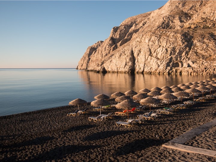 Santorini caldera cliffs viewed from the sea, showing white buildings against the volcanic rock and blue sea