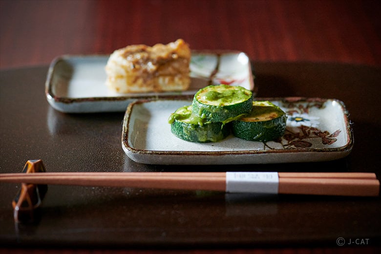 Two pieces of mochi stacked on top of each other, dusted with a fine white powder, showcasing its soft and chewy texture.