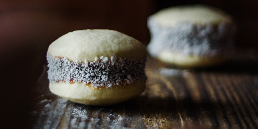 A close-up shot of an alfajor de maicena, showcasing the layers of dulce de leche and the texture of the coconut flakes.