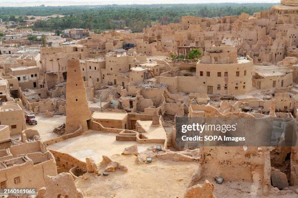 A panoramic view of the Huacachina oasis at golden hour, with luxury glamping tents subtly visible in the background