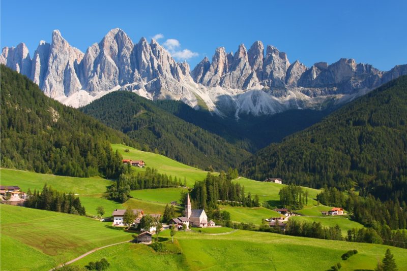 A picturesque alpine lake surrounded by mountains and lush greenery in the Dolomites.