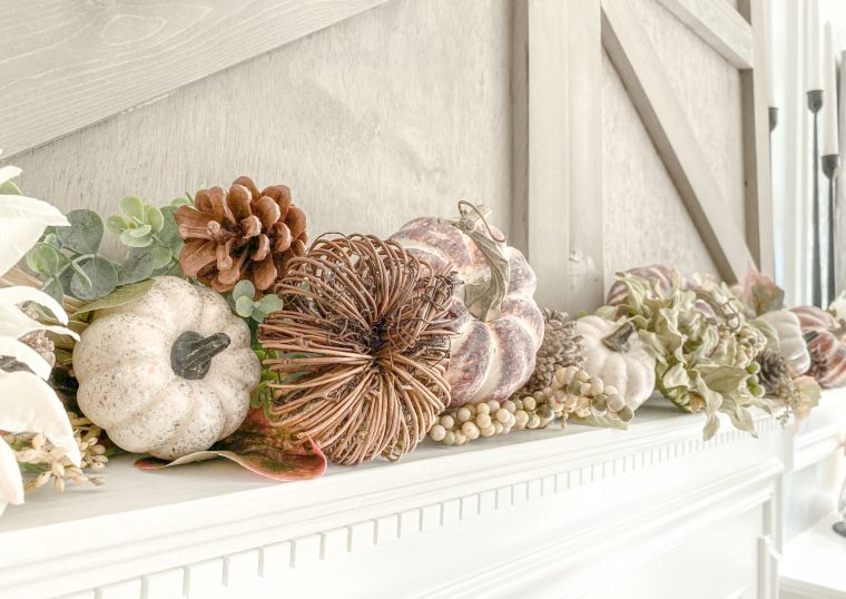 A rustic farmhouse kitchen features autumn decor, including pumpkins and wooden elements, creating a warm and inviting space.