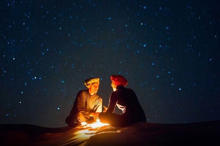 A weathered Filson Dry Tin Cloth Backpack sits in the vast, orange expanse of the Namib Desert, symbolizing preparedness for a self-sufficient journey.