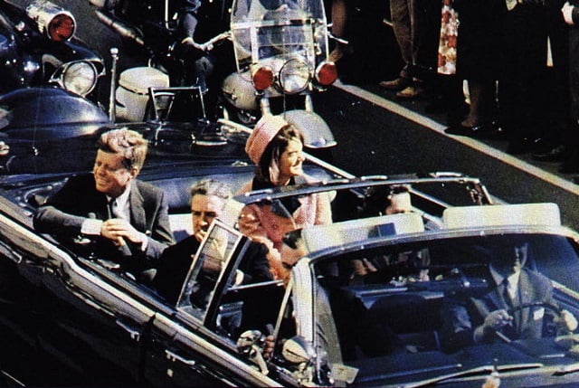 Close-up photograph of declassified documents, with large black redactions obscuring text. A sense of crucial information being hidden from view is palpable.