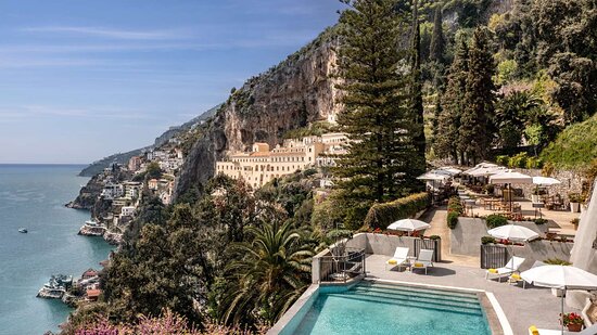 Panoramic view of the Azure Oasis Resort cascading down the Amalfi Coast cliffside, showcasing its prime location and stunning ocean views.