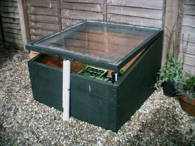 A front view of a wooden cold frame with a glass lid.