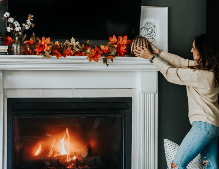 A vintage-style living room featuring a thrifted wooden coffee table adorned with autumn-themed decorations and a stack of old books.