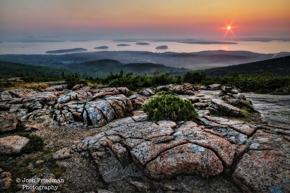 A biker riding along one of Acadia National Park's smooth gravel carriage roads, surrounded by dense spruce-fir forests