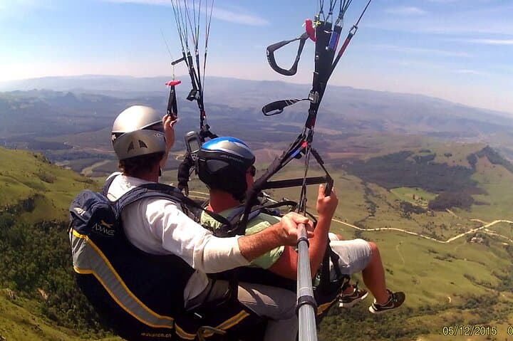 A vibrant image of a paraglider soaring above the Drakensberg Mountains, capturing the sense of freedom and awe experienced during flight
