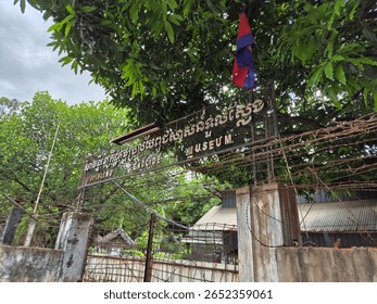 A barbed wire fence at Tuol Sleng Genocide Museum under a cloudy sky