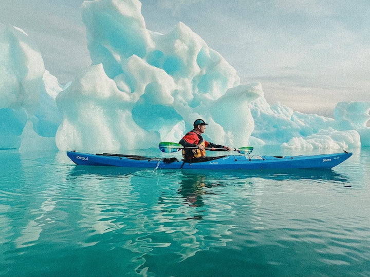 An ice surfer gliding across the frozen surface of Lake Superior with a windsurfing sail, showcasing the vastness of the lake and the dynamic movement of the surfer. The alt text emphasizes the action and the unique combination of windsurfing and ice skating.