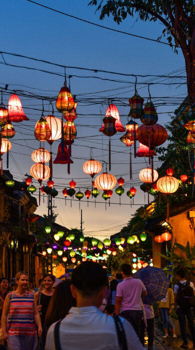 A narrow street in Hanoi's Old Quarter is adorned with countless vibrant lanterns strung overhead for the Mid-Autumn Festival, creating a dazzling spectacle of light and color.