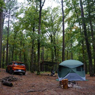 Emily struggling to hammer in tent stakes with a rock